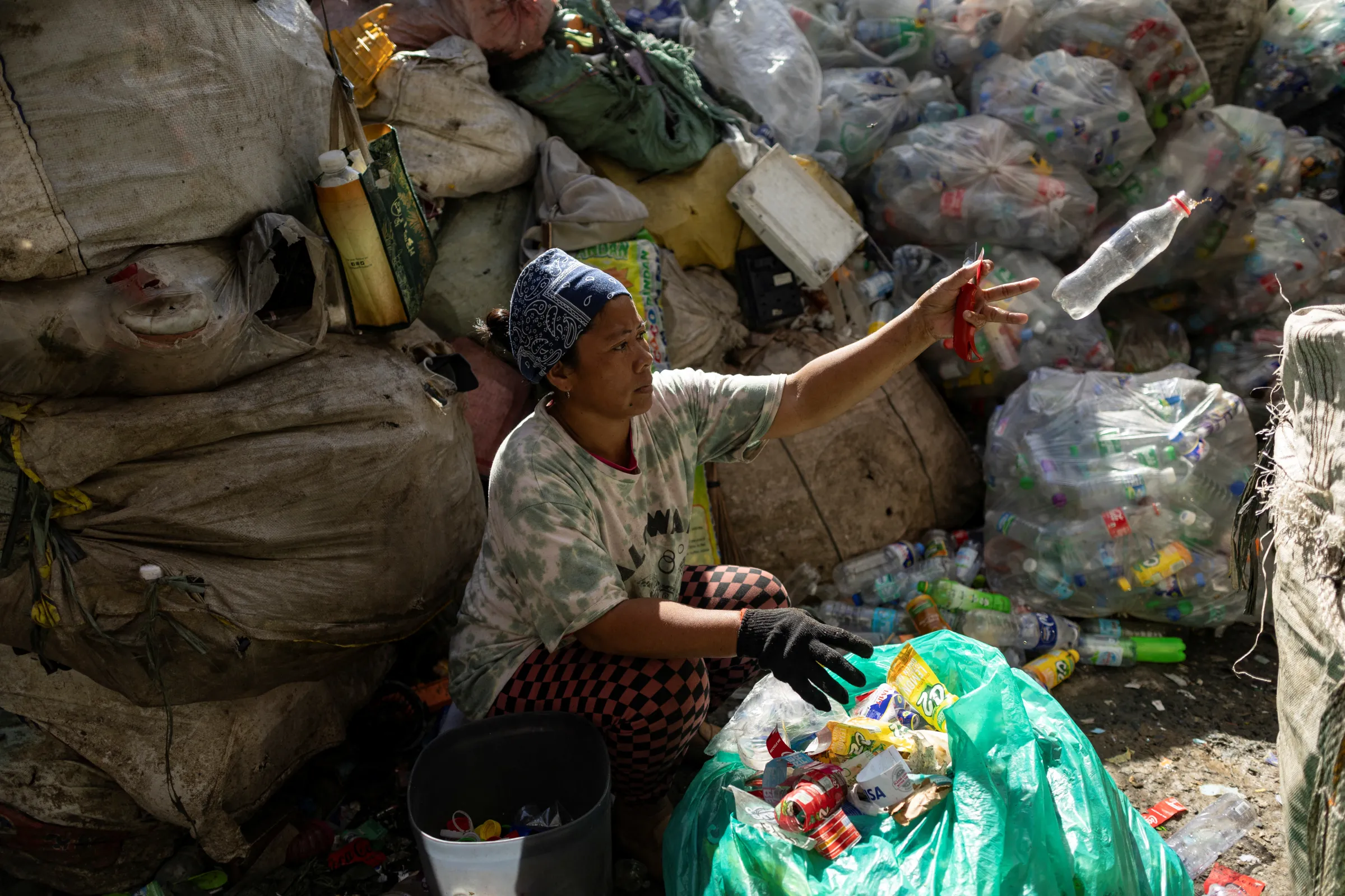 A worker sorting collected plastic bottles at a recycling facility