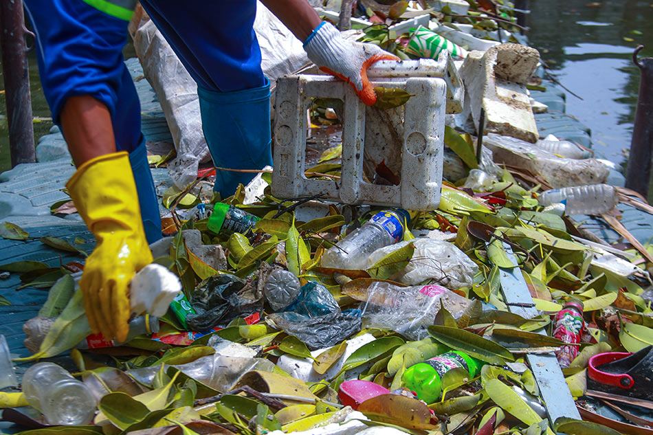 Waste pickers clearing plastic debris from a waterway